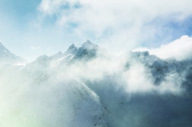 Dağ zirveleri ve günbatımı bulutlara. 