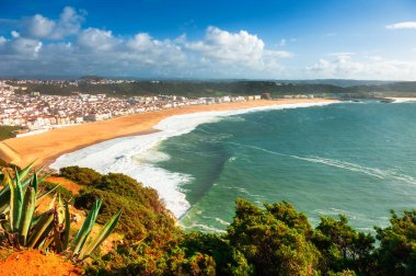 Portekiz, Nazare 'deki Atlantik Okyanusu kıyısında dalgalar. Kasabanın ve plajın panoramik manzarası. Sonbahar manzarası