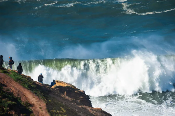 People watching big waves in Nazare, Portugal. In this place the biggest waves in the world due to the underwater canyon