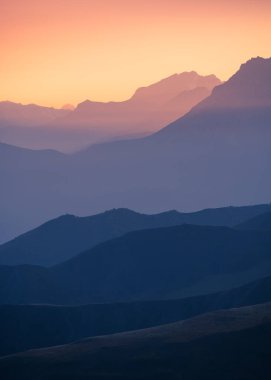 Gün batımında dağ sırası. Pembe gökyüzü olan mavi dağlar. Güzel sonbahar manzarası. Ingushetia, Kuzey Kafkasya, Rusya. 