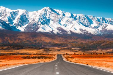 Sonbahar dağlarında güzel bir yol. Chuysky yolu ve Altai, Sibirya, Rusya 'daki Kuzey Chuya dağ sırtı manzarası. Karla kaplı dağ tepeleri ve sarı sonbahar ormanı