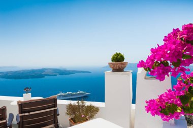 Santorini Adası, Yunanistan 'da beyaz mimari. Terasta deniz manzaralı çiçekler. Seyahat hedefleri kavramı