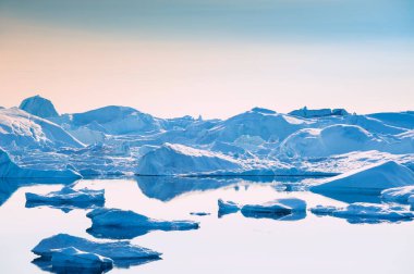 Ilulissat 'taki buzdağı, Grönland' ın batı kıyısında. Buzdağlarının yansıması olan sakin bir su.