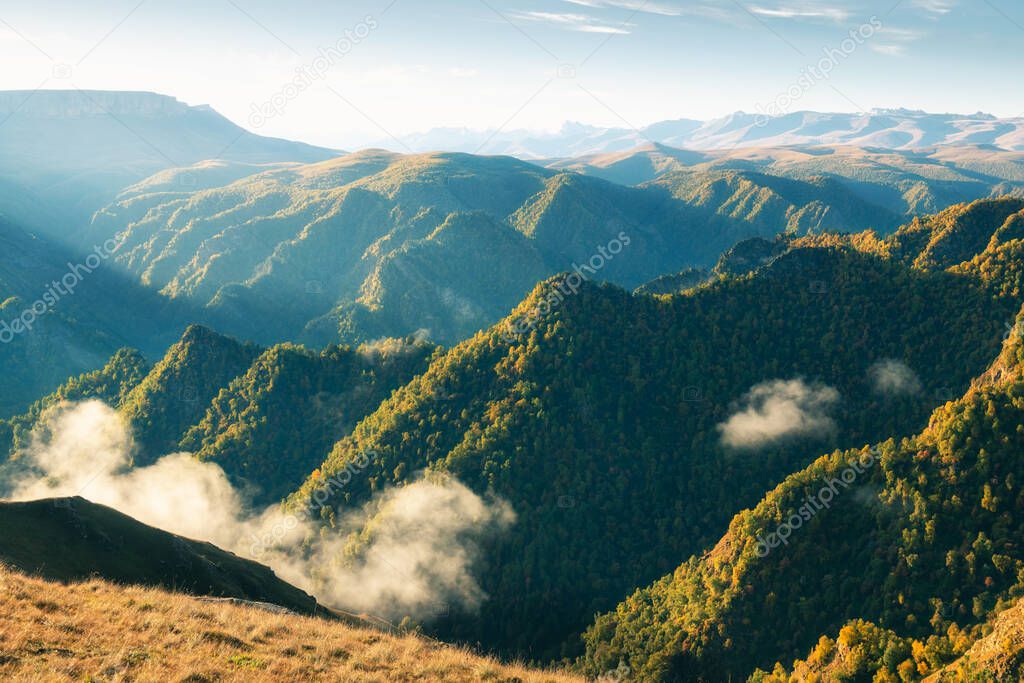 Green mountains with clouds at sunrise. Gil-Su valley in North Caucasus, Russia. Beautiful autumn landscape
