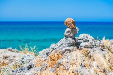 Bir kayalık sahil deniz arka planda taşları dengede.