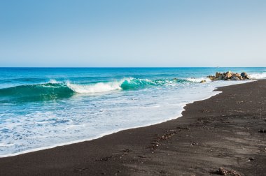 Güzel bir plaj turkuaz su ve siyah kum ile.