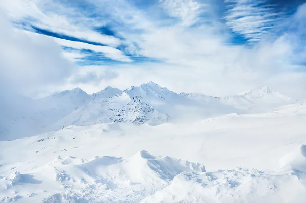 Invierno montañas cubiertas de nieve y cielo azul con nubes blancas Imágenes de stock libres de derechos