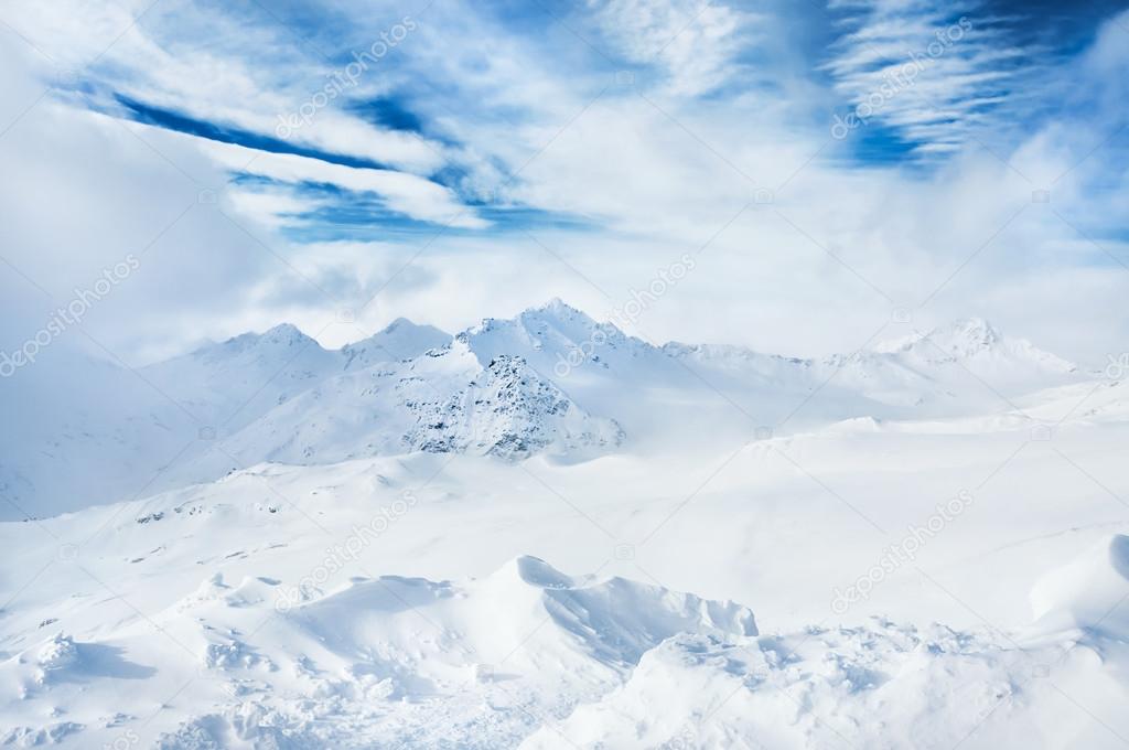 Winter snow-covered mountains and blue sky with white clouds