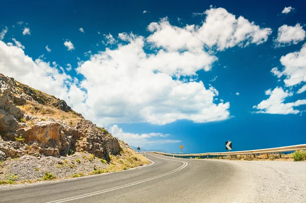 Road in the mountains and dark blue sky with white clouds — Stock Photo, Image