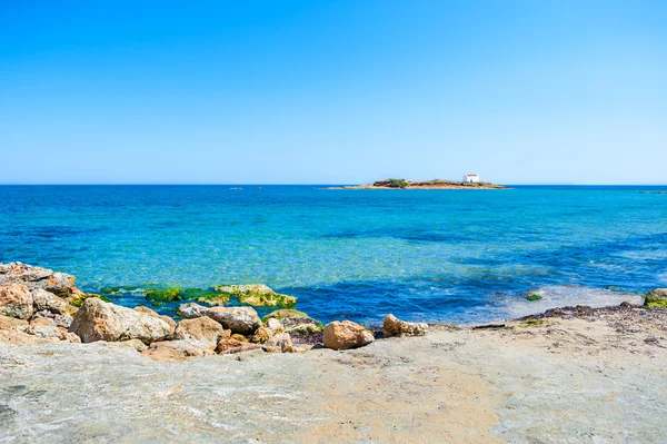 Beautiful beach with turquoise water and small island with chape — Stock Photo, Image