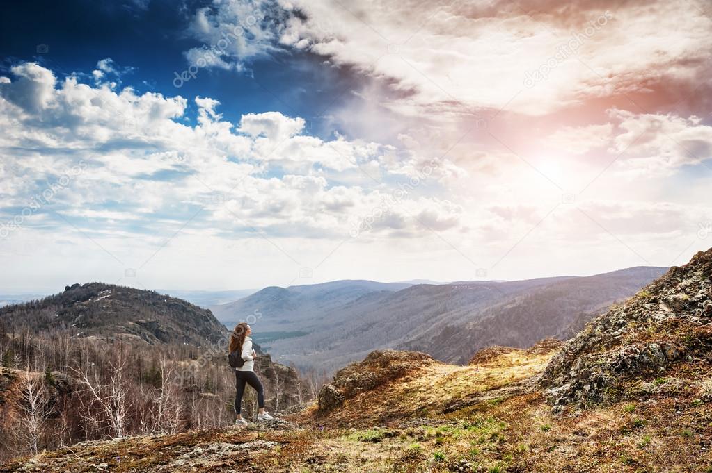 Woman hiker standing on top of the mountain and enjoying view at
