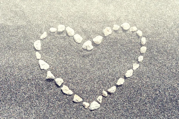 Kum arka plan üzerinde kalp şeklinde taş — Stok fotoğraf