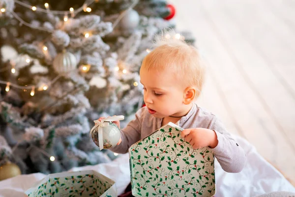 クリスマスツリーの近くにプレゼントボックスを開く幸せな小さな赤ちゃんの男の子 クリスマスの朝のコンセプト — ストック写真