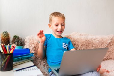 Evde dizüstü bilgisayarı ve sanal sınıfta ders çalışan küçük bir okul çocuğu. Karantina sırasında uzaktan eğitim ve öğrenme, e-öğrenme, çevrimiçi öğrenme kavramı