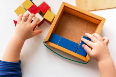 Bebek ahşap bloklarla oynuyor bir kalıp oluşturuyor, ellere odaklanıyor. Nikitin unicube oyunu
