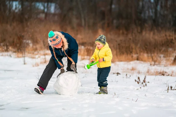 幸せな子供たちは冬に雪だるまを屋外にするために大きな雪玉を作ります 冬の野外活動 — ストック写真