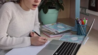 Güzel liseli kız evde ders çalışıyor. Eğitim kitapları ve defter masanın üstünde. Uzaklık öğrenimi çevrimiçi eğitim