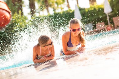 Mutlu güzel kızlar tatil köyündeki havuzda eğleniyor.