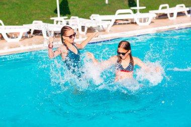 Mutlu güzel kızlar tatil köyündeki havuzda eğleniyor.