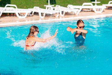 Mutlu güzel kızlar tatil köyündeki havuzda eğleniyor.