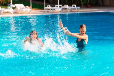 Mutlu güzel kızlar tatil köyündeki havuzda eğleniyor.