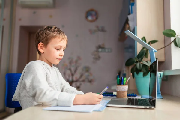 学校の宿題をする家で勉強するかわいい少年 テーブルの上で本やノートを訓練する 遠隔オンライン教育 — ストック写真