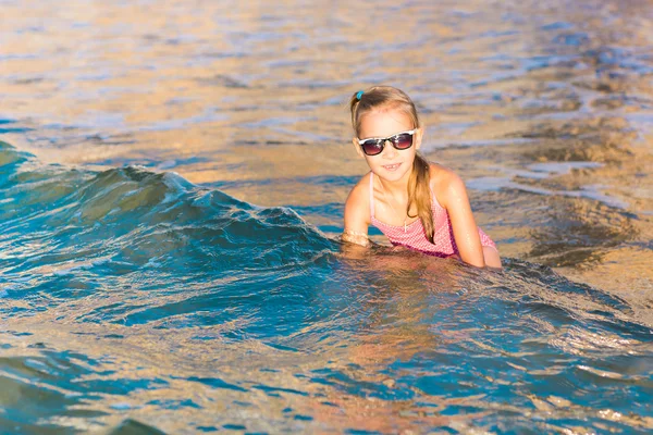 Adorable niña jugando en el mar en una playa —  Fotos de Stock