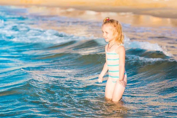 Adorable niña jugando en el mar en una playa —  Fotos de Stock