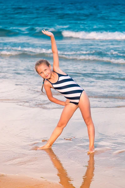 Beautiful little girl excercising on the beach — Stock Photo, Image