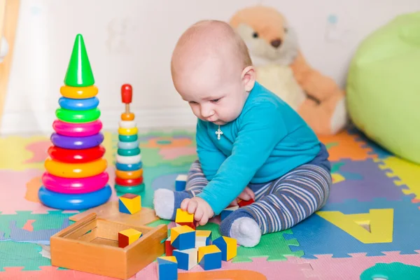 Carino piccolo bambino che gioca con giocattoli colorati in casa — Foto Stock