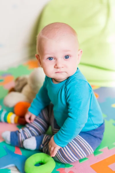 Niedliches kleines Baby spielt mit buntem Spielzeug drinnen — Stockfoto