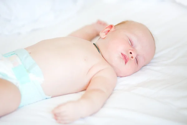 Friedliches Neugeborenes liegt schlafend auf einem Bett — Stockfoto