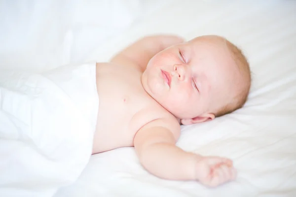 Friedliches Neugeborenes liegt schlafend auf einem Bett — Stockfoto