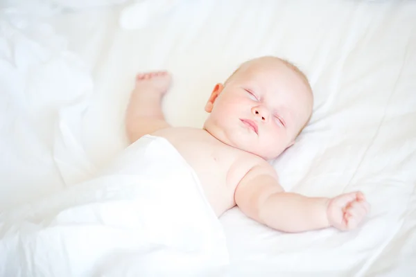 Fredlig nyfödda barnet ligger på en säng sover — Stockfoto