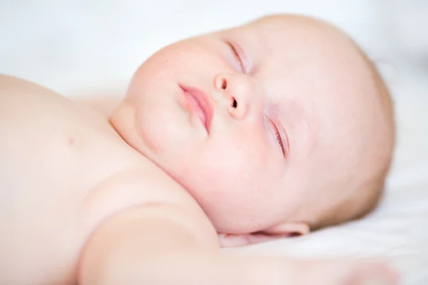 Friedliches Neugeborenes liegt schlafend auf einem Bett — Stockfoto