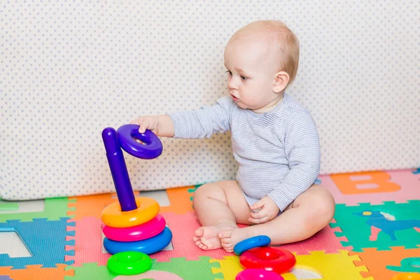 Niedliches kleines Baby spielt mit buntem Spielzeug — Stockfoto