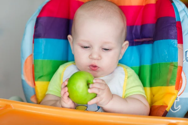 Adorável bebê comendo maçã em cadeira alta — Fotografia de Stock