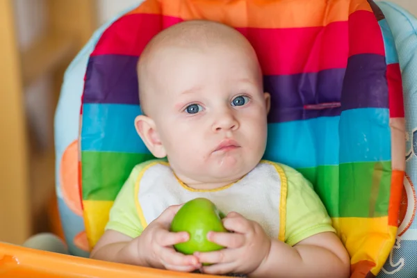 Schattige baby eten apple in hoge stoel — Stockfoto