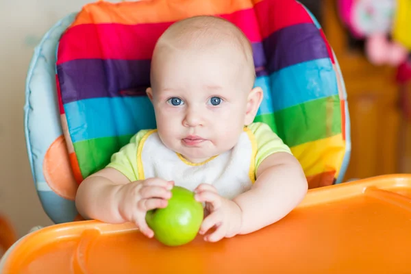 Adorável bebê comendo maçã em cadeira alta — Fotografia de Stock