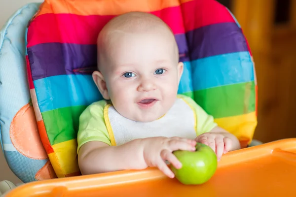 Entzückendes Baby isst Apfel im Hochstuhl — Stockfoto