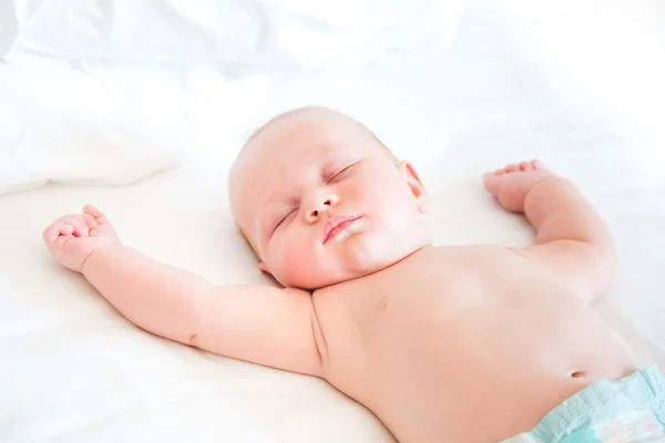 Friedliches Neugeborenes liegt schlafend auf einem Bett — Stockfoto