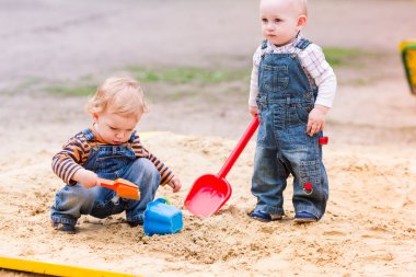 Two baby boys playing with sand clipart