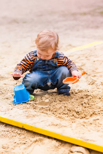 Милый мальчик играет с песком — стоковое фото