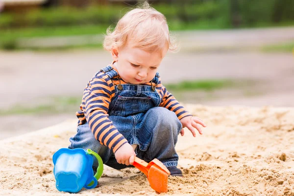Niedlicher kleiner Junge spielt mit Sand lizenzfreie Stockfotos