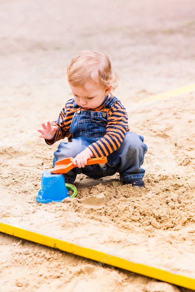 Cute baby boy playing with sand