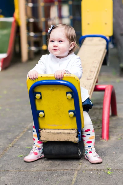 Cute baby girl on a seesaw swing — Stock Photo, Image