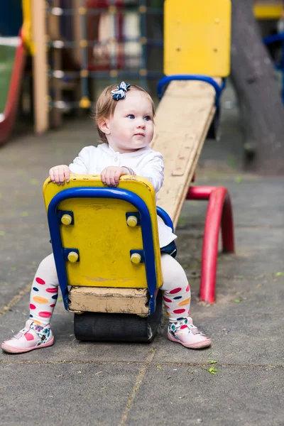 Cute baby girl on a seesaw swing — Stock Photo, Image