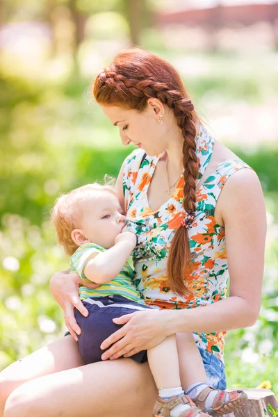 Beautiful happy mother breastfeeding outdoor — Stock Photo, Image