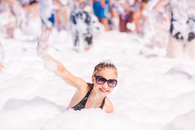 Cute little girl having fun at foam party.