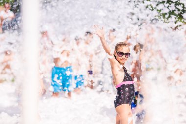 Cute little girl having fun at foam party.